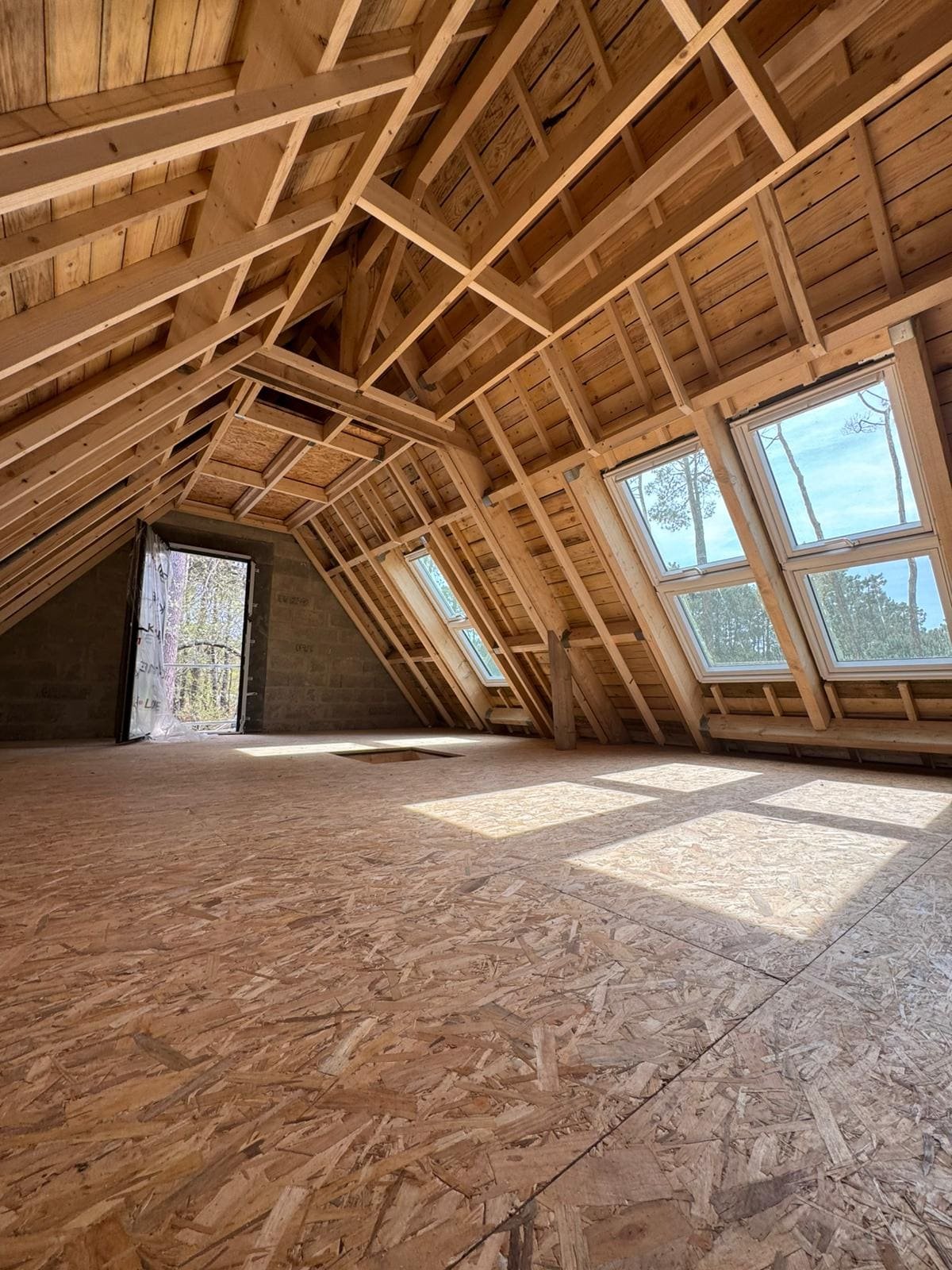 Combles bruts avant travaux : charpente bois apparente, velux posés, plancher OSB, Carnac